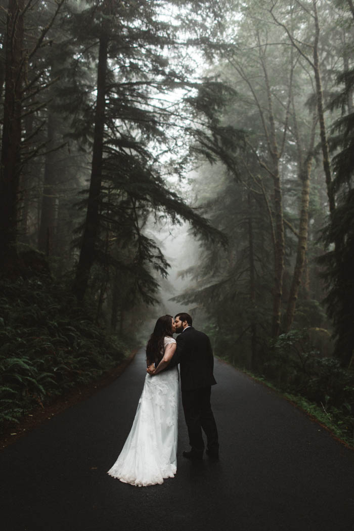 bride and groom kissing in foggy forest