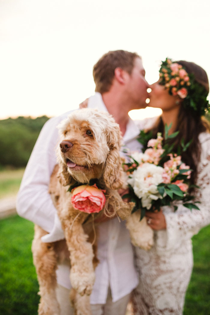 bride and groom kissing and holding dog