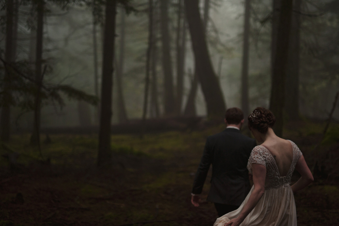 bride and groom walking through the woods