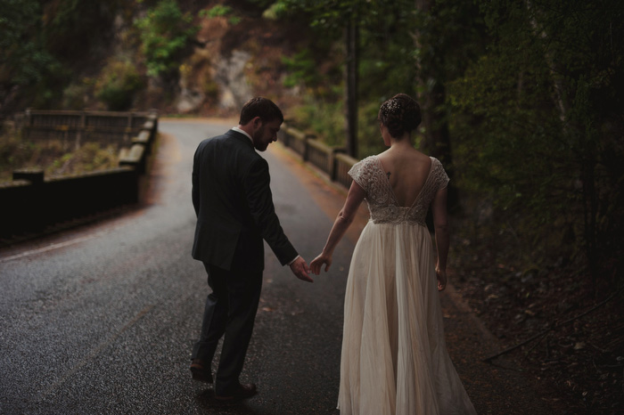 bride and groom walking down forest path