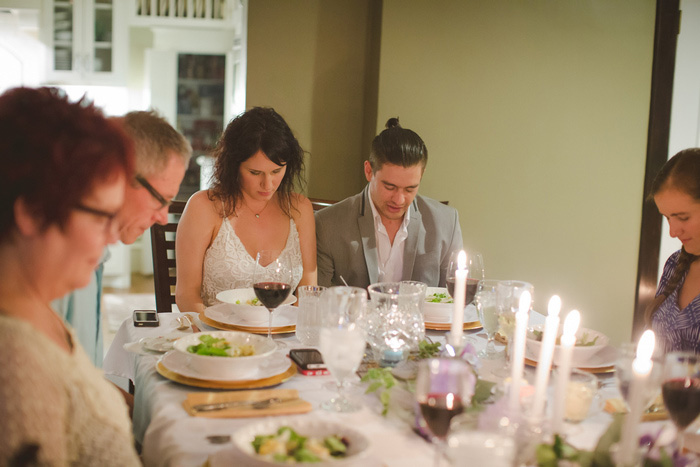 bride and groom bowing heads at dinner