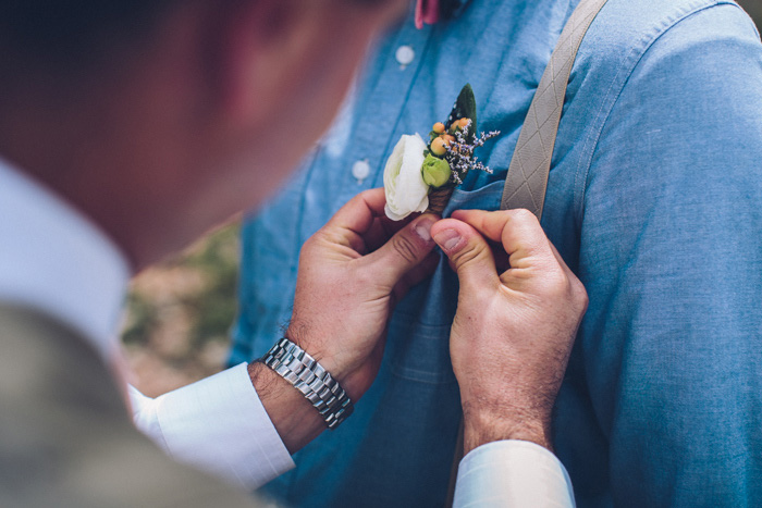 boutonniere being pinned on groom