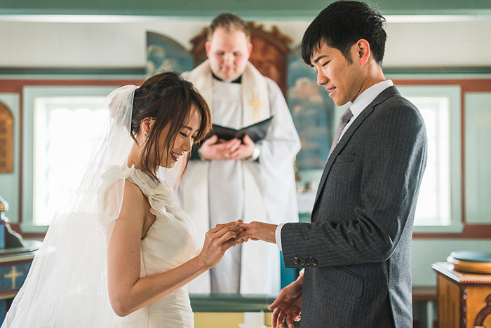 bride putting ring on groom's finger