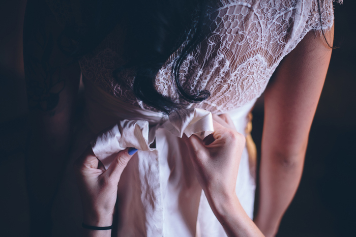 bow being tied on bride's dress