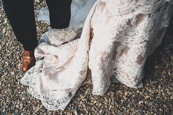 detail of bottom of bride's dress and groom's shoes