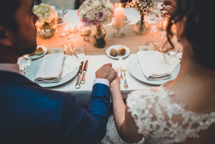 bride and groom holding hands during reception dinner