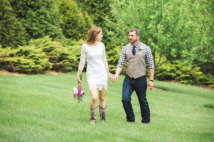 bride and groom waking across grass