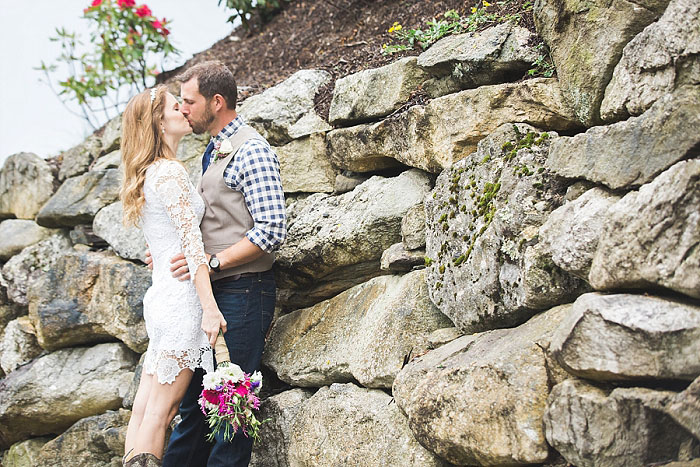 bride and groom kissing by rocks