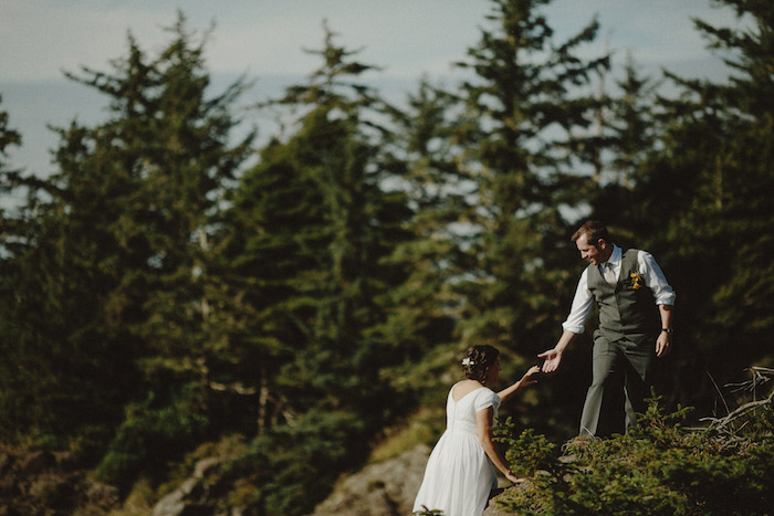 groom helping bride climb the rocks