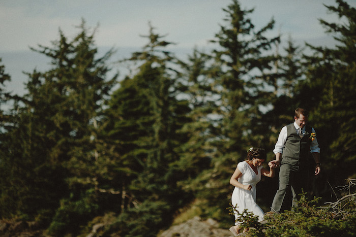 bride and groom climbing on rocks