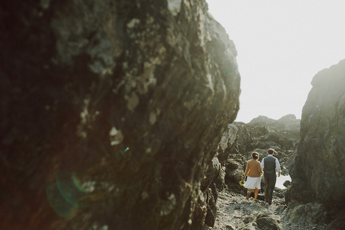 bride and groom walking on rocky beach