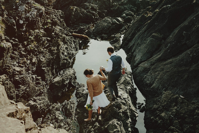 bride and groom walking on the rocks