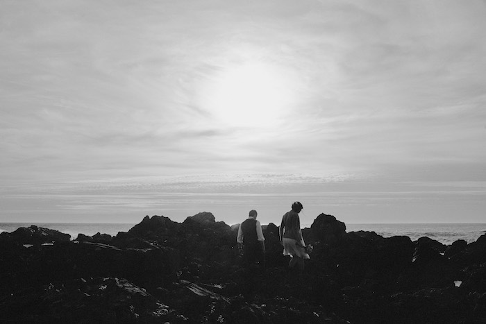 bride and groom climbing on rocks