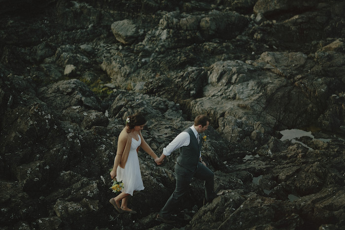 bride and groom walking on rocky coast