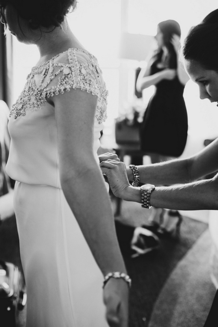 bride getting buttoned into her dress