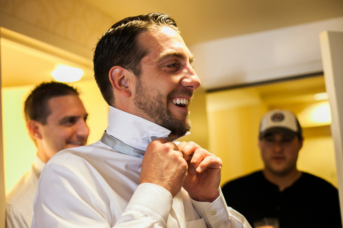 groom tying his bow tie