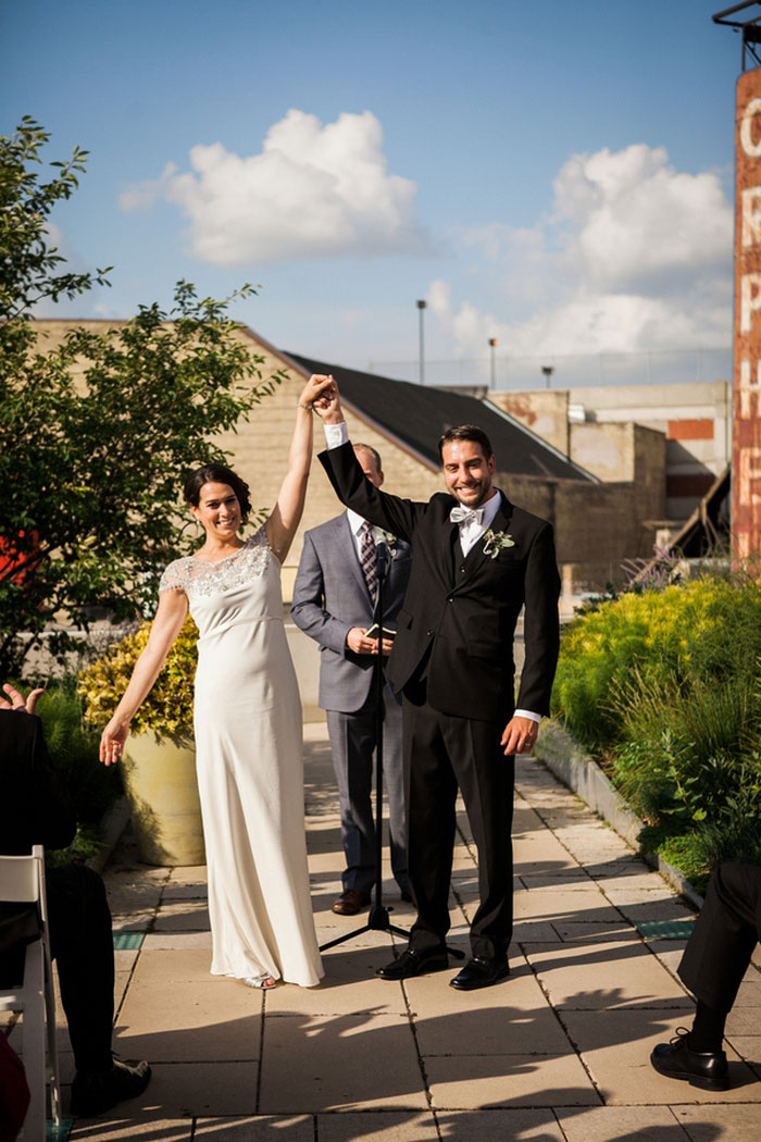 bride and groom rainy their arms in celebration at end of ceremony