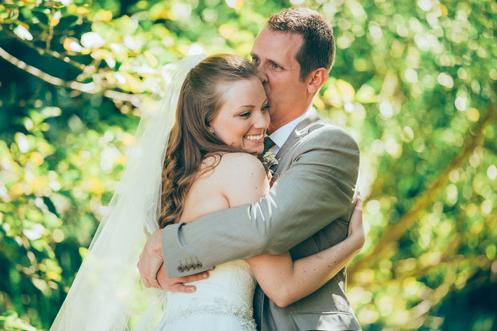 groom hugging and kissing bride on forehead