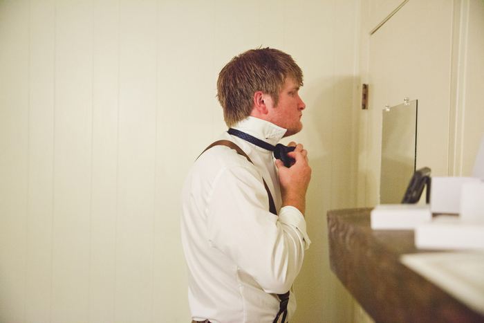 groom tying his bow tie