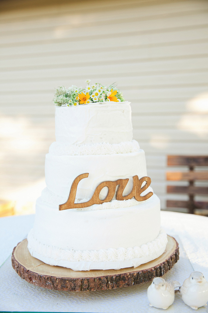 wedding cake with wild flowers and love sign