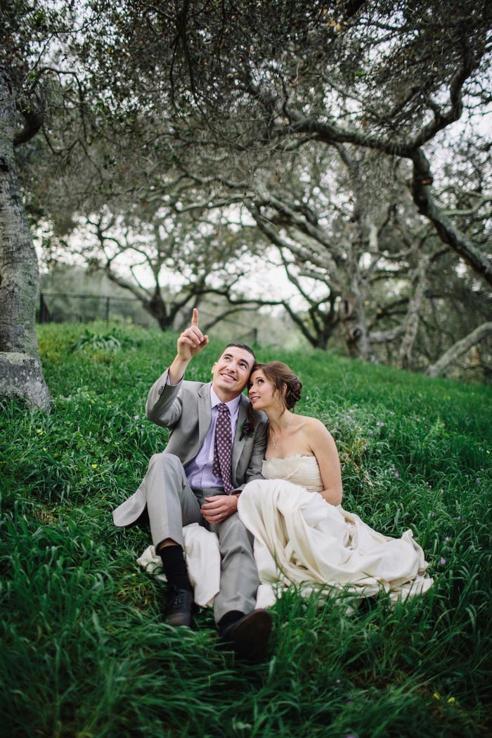bride and groom sitting in the grass