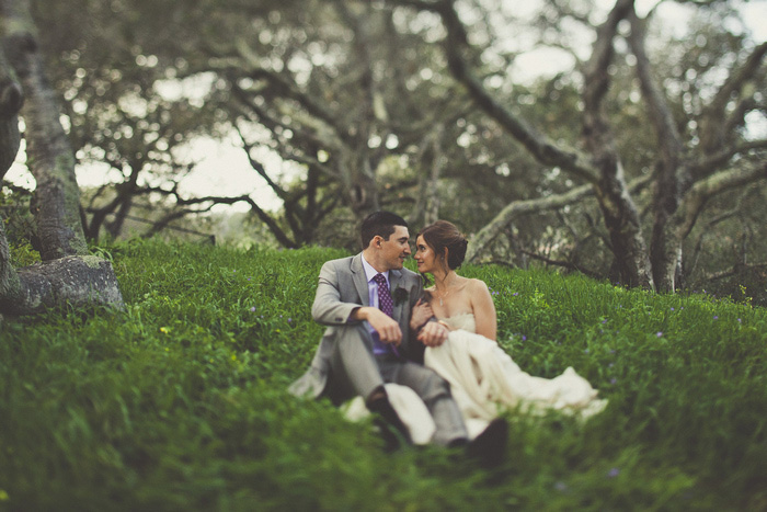 bride and groom sitting in the grass