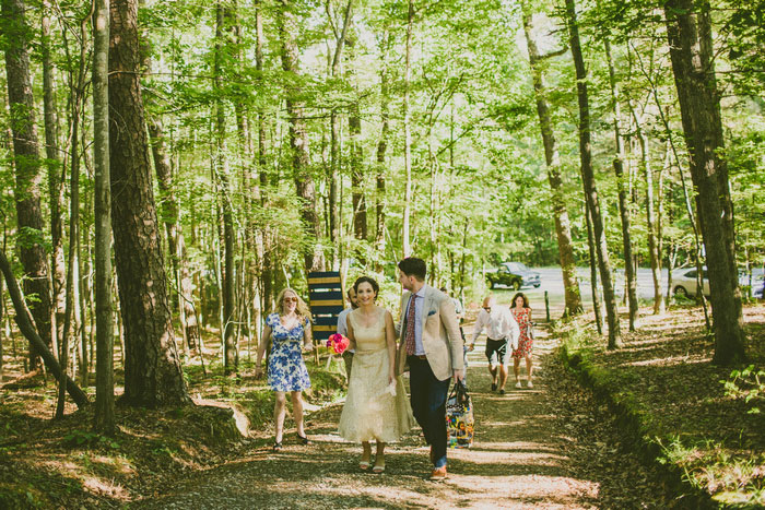 bride and groom walking to ceremony site in the woods