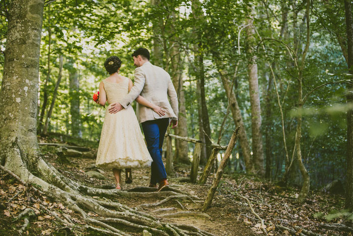 bride and groom walking through woods