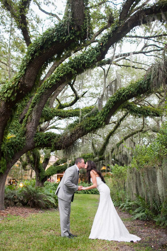 bride and groom kissing under tree