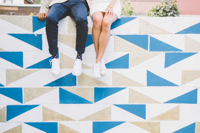 bride and groom sitting on colourful wall