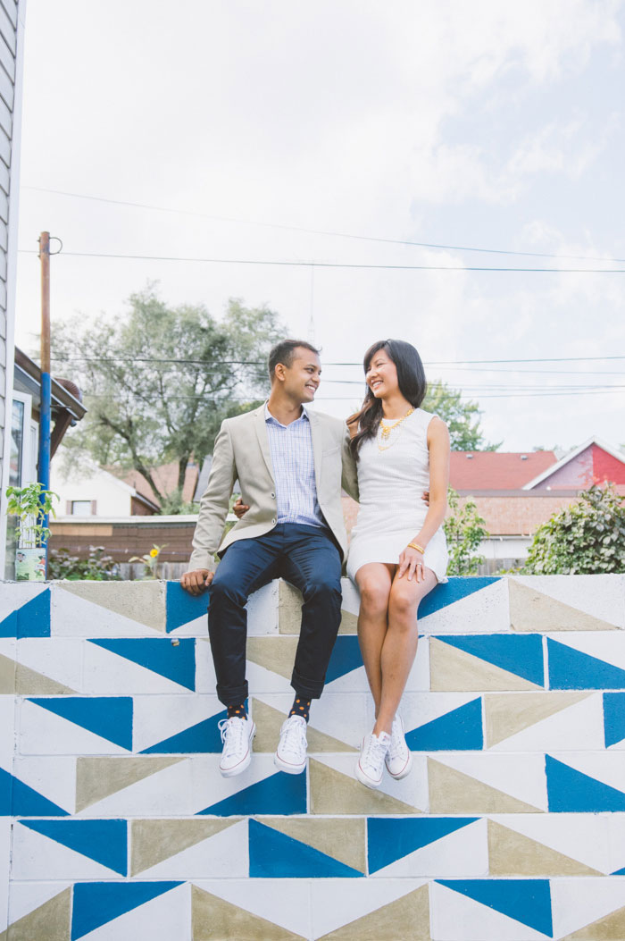bride and groom sitting on colourful wall