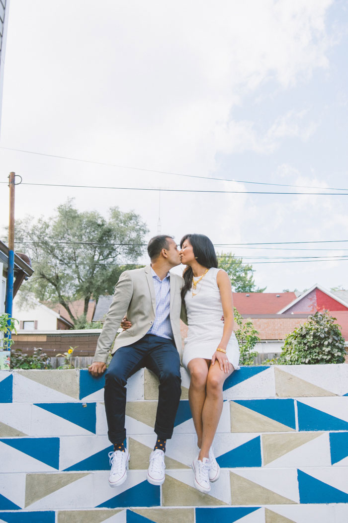 bride and groom sitting on colourful wall