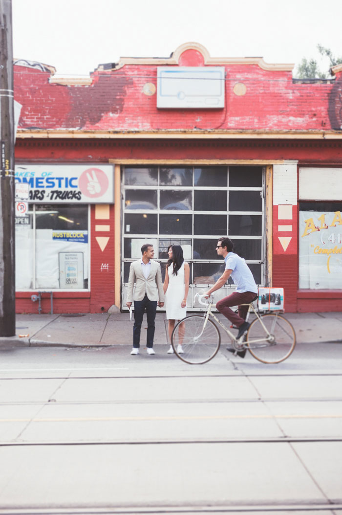 bride and groom portrait with cyclist riding by