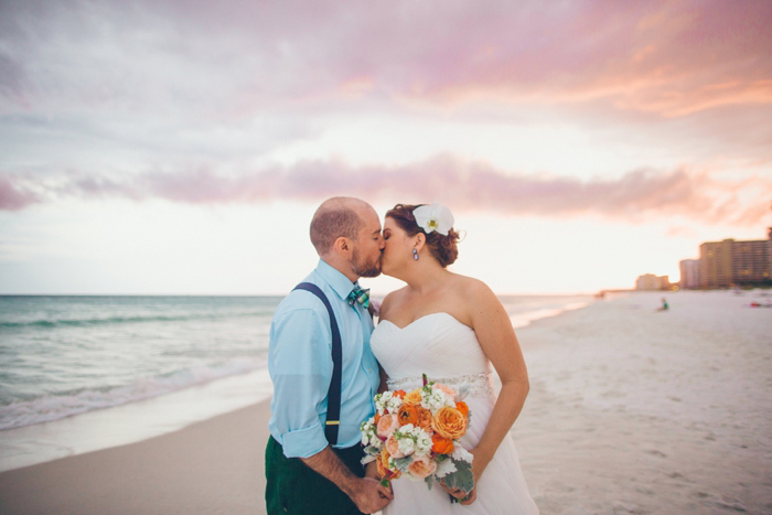 bride and groom kissing on the beach at sunset