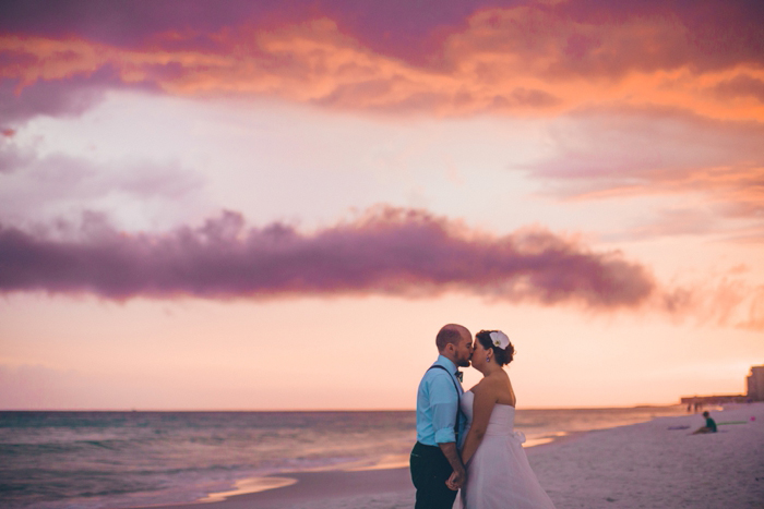 bride and groom kissing on the beach at sunset