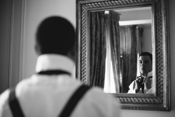 groom tying his bow tie