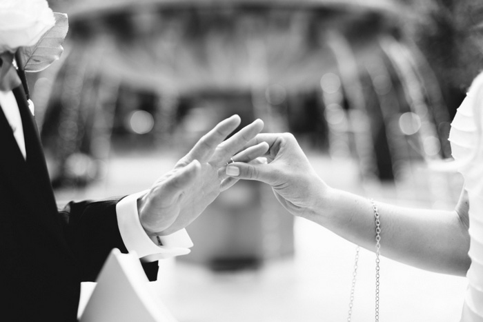 bride putting ring on groom's finger