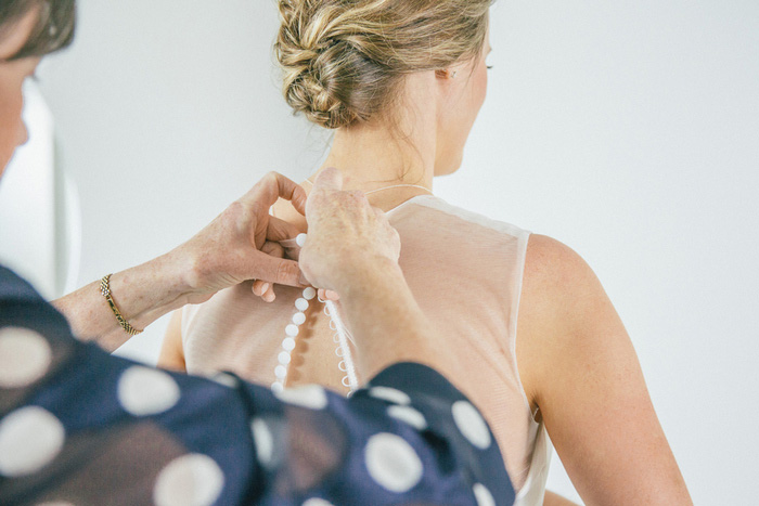 bride being buttoned into dress