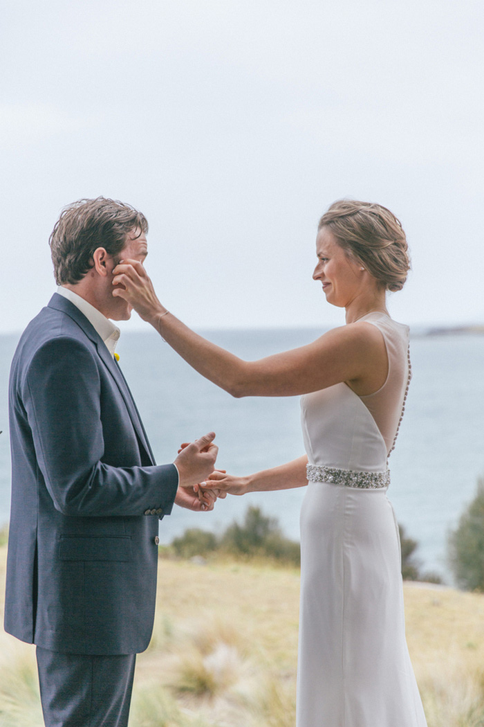 bride wiping away groom's tears during ceremony