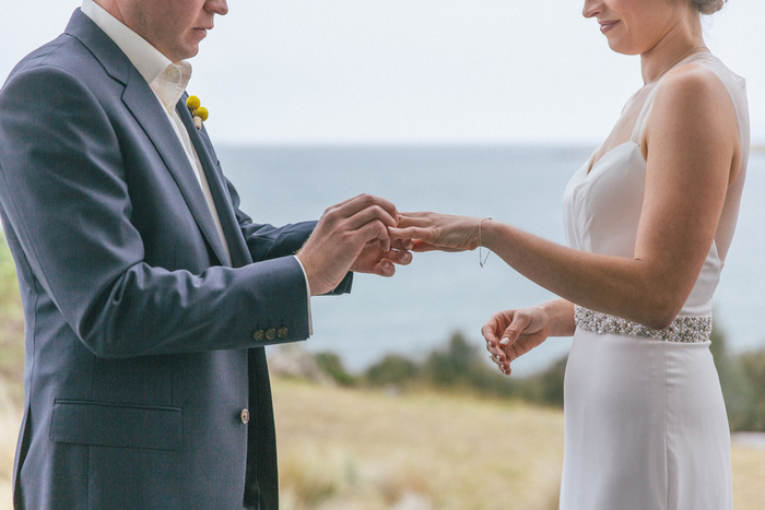 groom putting ring on bride's finger