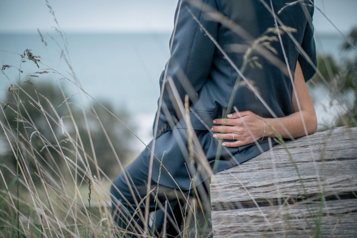 bride and groom sitting on log on the beach