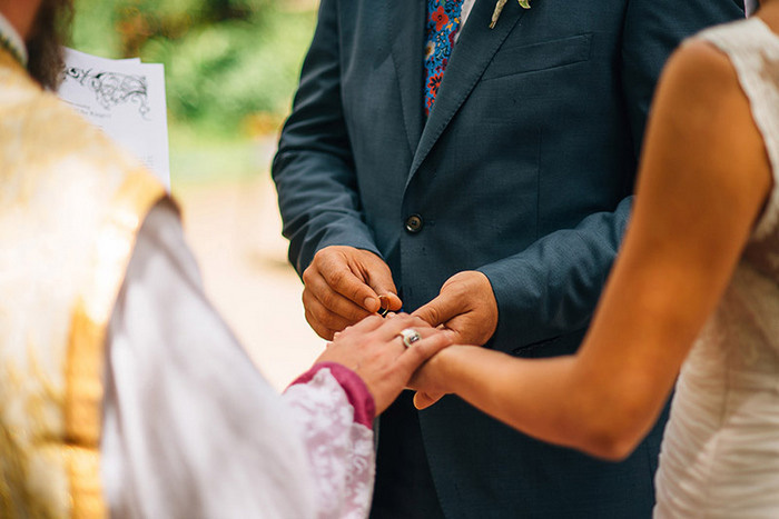 groom putting ring on bride's finger
