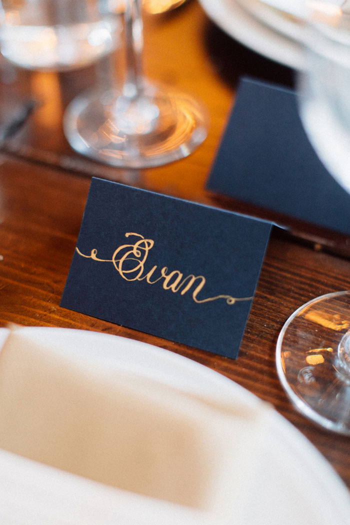 gold calligraphy on navy place cards