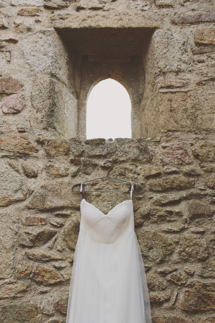 wedding dress hanging on stone wall