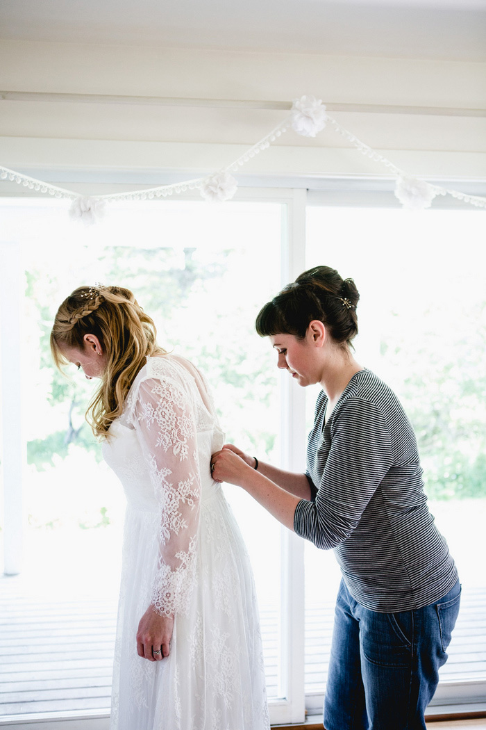 bride getting buttoned into dress