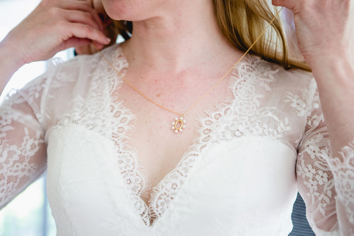 bride putting o n necklace