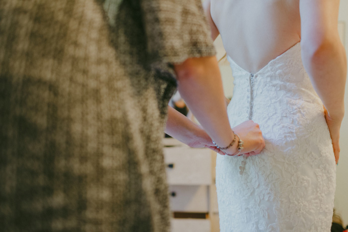 bride getting her dress buttoned up