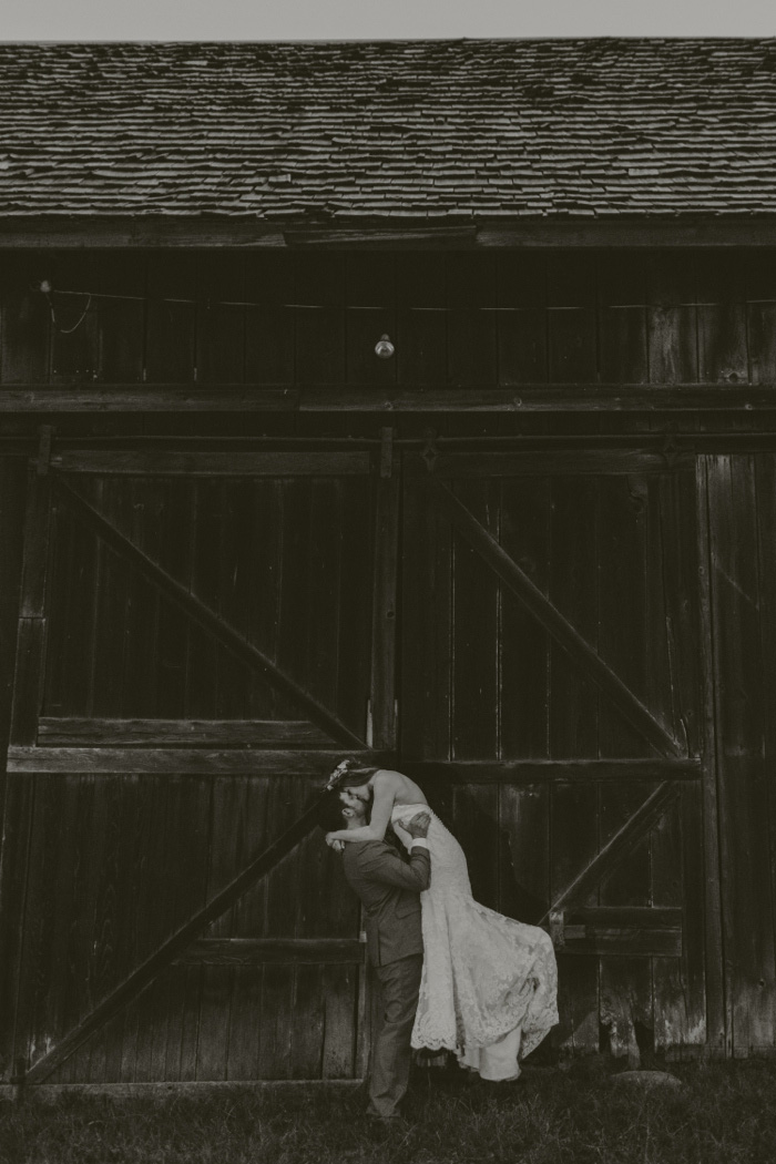 groom lifting bride up as he kisses her