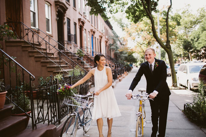 bride and groom wheeling bikes down street