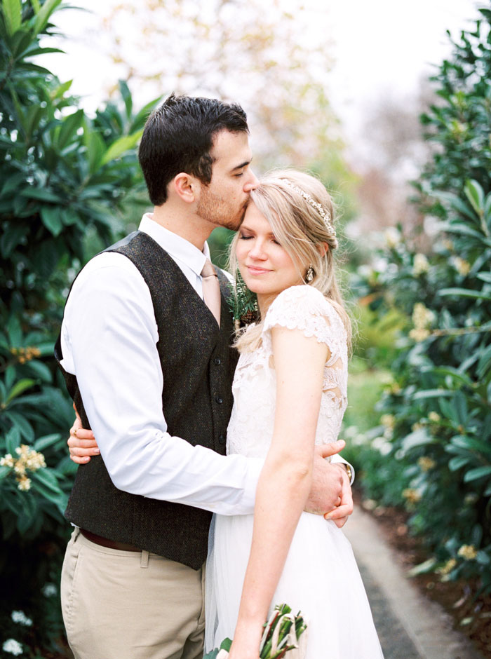 groom kissing bride on head